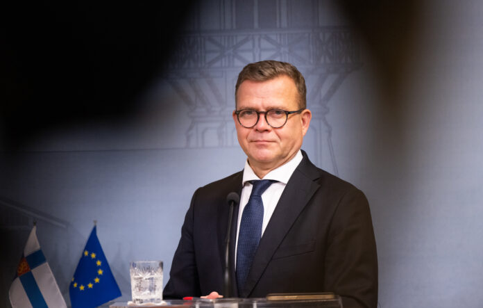 Petteri orpo vid ett podium. I bakgrunden syns Finlands och EU:s flagga.