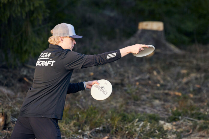 En svartklädd man håller i en frisbee