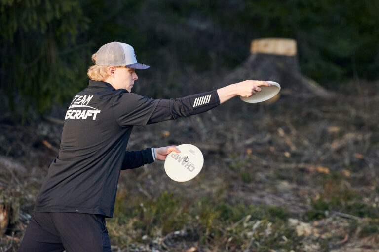 En svartklädd man håller i en frisbee