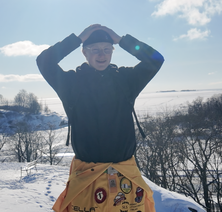 Ung man står i ett vinterlandskap med händerna på huvudet.